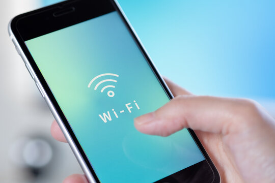 手に持ったスマホに表示されたWi-Fi (ワイファイ) アイコン。オリジナルイメージ画像