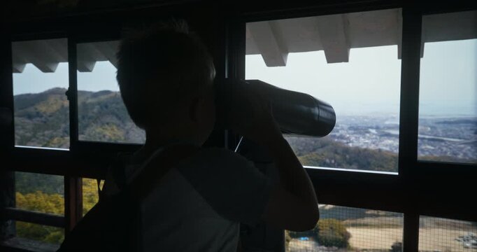 Silhouette of Boy Using Binoculars at Observation Deck In Hiroshima Japan