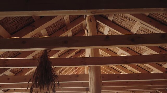 Traditional architecture featuring an interior view of a wooden frame structure with a thatched roof, showcasing ecological building materials and rustic craftsmanship in a country house
