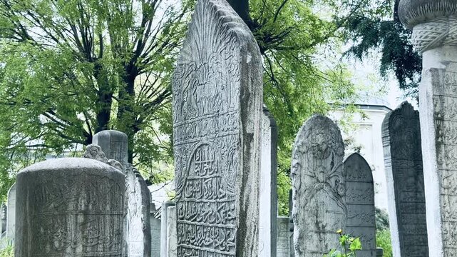 Ancient ottoman tombstones with engraved Quran verses and arabic calligraphy at historic Eyup Sultan Cemetery in Istanbul. Holy islamic scripture, sacred graveyard monuments and cultural heritage.
