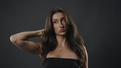 Fototapeta premium Woman posing in studio reflecting on thoughts, wearing gold jewelry