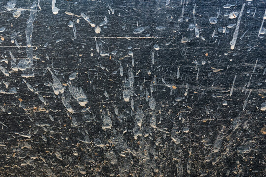 Dirty black surface with dried mud splatter, textured background showing rough, messy, and weathered appearance, suitable for grunge or industrial design concepts