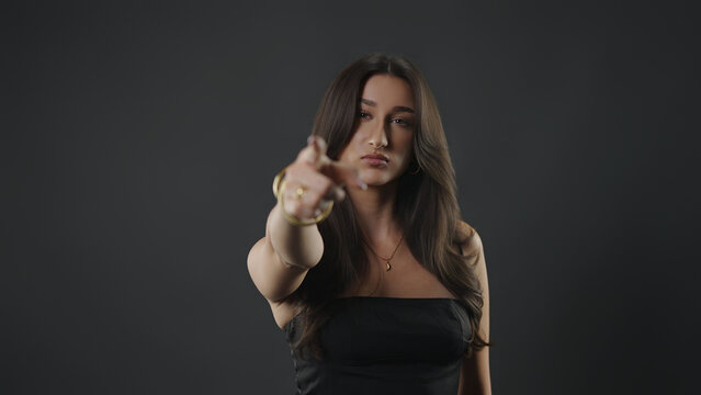 Young woman confidently pointing a finger forward, making an accusatory gesture