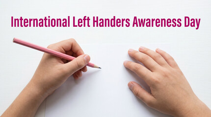 Left handed person writing on white paper for International Left Handers Awareness Day.