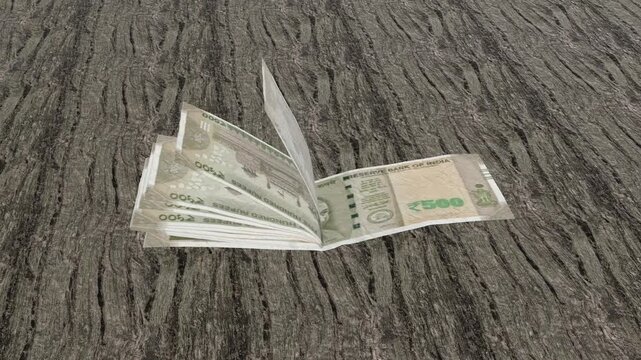 Multiple Indian 500 Rupee banknote slightly folded in the middle, resting on a textured dark wooden floor.