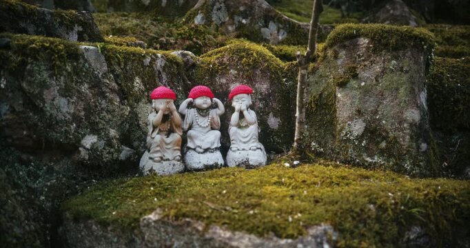 Tiny Three Jizo Statues With Red Knit Caps on Moss-Covered Rock In Japan - Medium, Steady Cam Shot