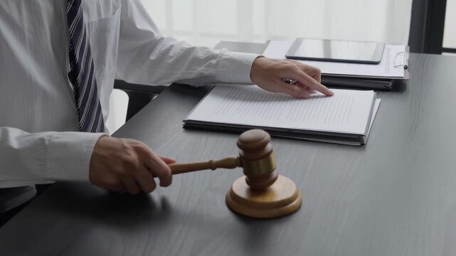 Lawyer using reading legal document and knocking gavel