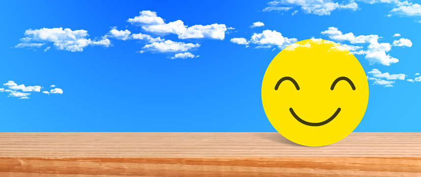 Happy yellow smiling face on wooden table with cloudy sky perfect for positive emotional feedback and joyful life concepts