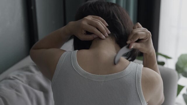Asian mature woman using gua sha massage her neck