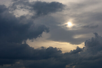 Obraz premium The bright sun breaks through heavy storm clouds during a gloomy day. Contrast sunlight creates a dramatic effect on the dark overcast sky before a heavy storm begins. The natural phenomenon demonstra