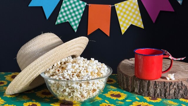 A bowl of popcorn on the table and colorful flags in the background. Decoration for a Brazilian June festival. Arrai&aacute;.