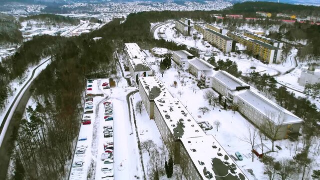 Aerial drone perspective of residential housing complex during winter season with snow covered buildings and roads.
