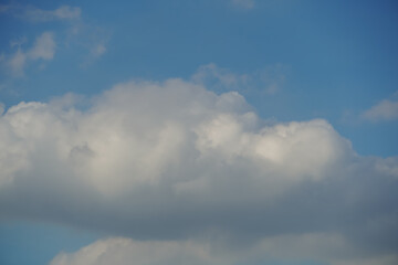 Obraz premium Fluffy white cumulus clouds drift across a clear blue sky on a bright day