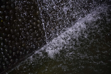 Close-up view of water cascading over dark, wet stones in a natural setting © Thanakrit