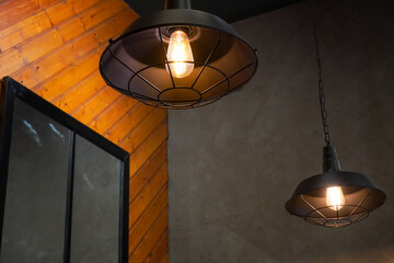 Industrial pendant lights with Edison bulbs illuminate a rustic interior space © Thanakrit