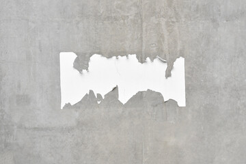 scrap of ripped advertising poster on raw concrete wall with copy space