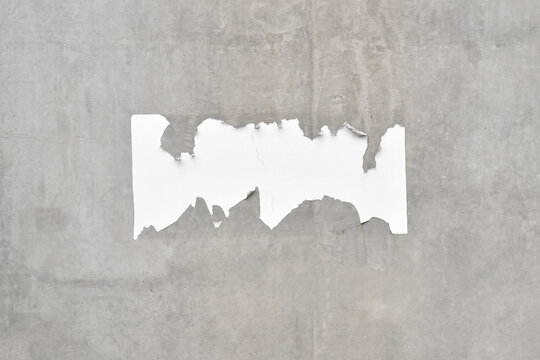 scrap of ripped advertising poster on raw concrete wall with copy space