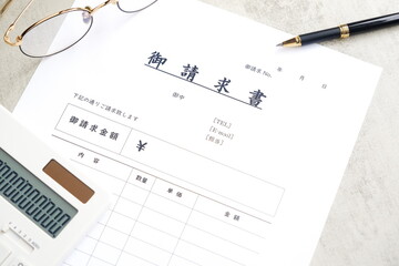 請求書 - 取引先へ宛てて請求書を準備する、ビジネスシーンのイメージ  © PJM