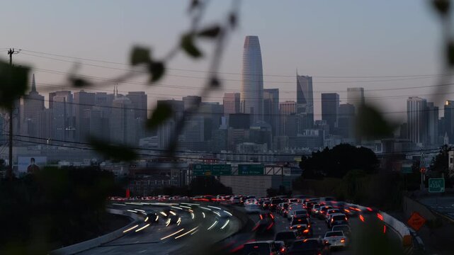 Beautiful day-to-night transition showing busy highway traffic with blurred light trails against the iconic San Francisco skyline with the Salesforce Tower and downtown skyscrapers