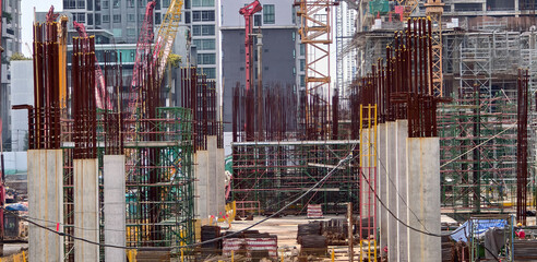 Active site construction background. showing concrete foundation pillars, exposed steel rebar scaffolding and heavy machinery building modern city high-rises © sutthichai