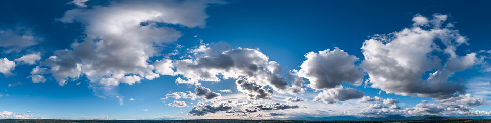 Obraz premium Dramatic Cloudscape Sky Over British Columbia Panorama With Sunlit Cumulus Clouds And Distant Mountains