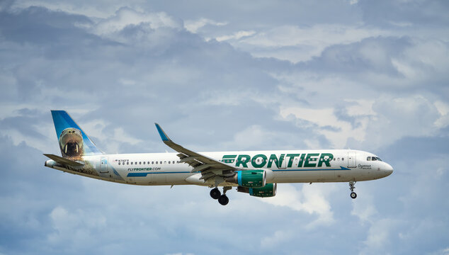 Frontier Airlines aircraft Airbus A321 airborne over the Dallas Fort Worth International Airport (DFW). Seymour the Walrus livery. Storm clouds.