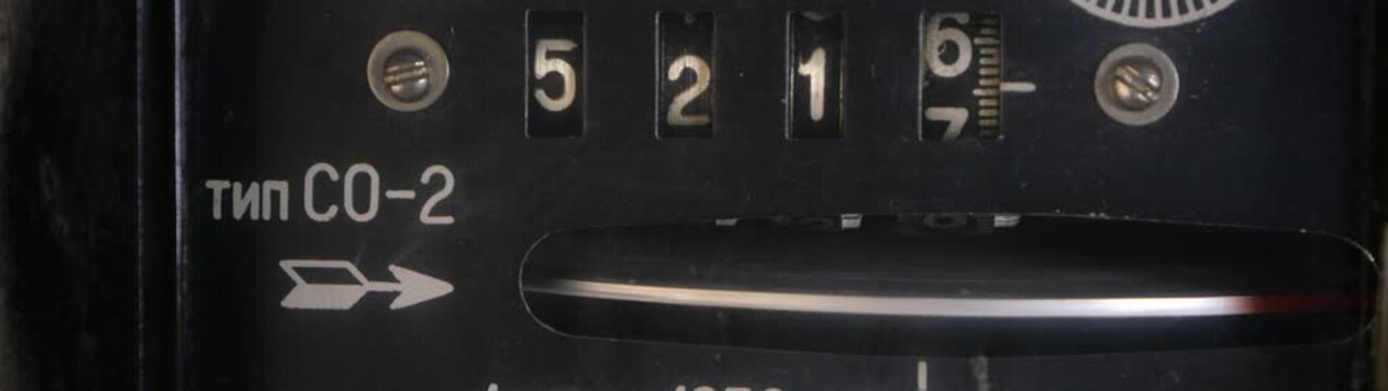 Old analog electricity meter showing current consumption with a spinning disk displaying numbers and cyrillic text.