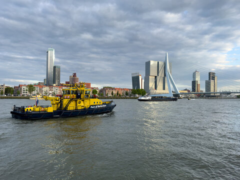 Port of Rotterdam workboat on the Nieuwe Maas river with Erasmus Bridge and modern skyline in Netherlands.