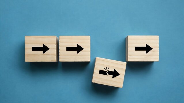 Wooden blocks with arrows on blue background showing a broken arrow symbol representing disruption or failure in a process
