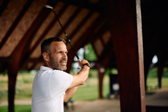 Golf player working on his golf technique while practicing at driving range.
