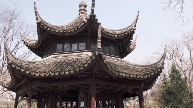 A low-angle shot showcases the tiered, sweeping tiled roofs and ornate wooden carvings of a traditional Chinese pagoda surrounded by bare winter trees.