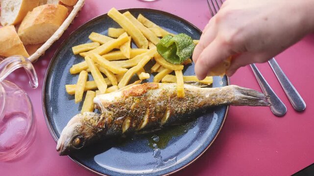 Fresh sea bass baked with herbs and potatoes. Fragrant cooked fish in the oven with a slice of lemon. High quality 4k footage