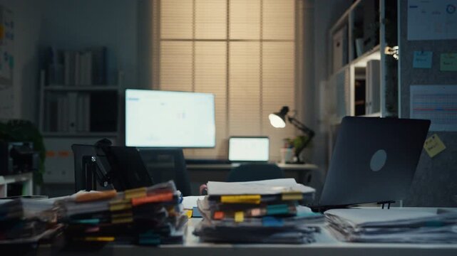 Stressed young Latin businessman walking to place tax document stack at desk in dark night office. Overworked overtime, heavy workload stress, tired employee, corporate business burnout concept.