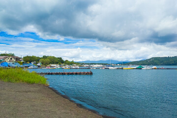 Obraz premium Moored boats and floating dock on Lake Yamanaka under dramatic clouds (Yamanakako, Yamanashi, Japan)