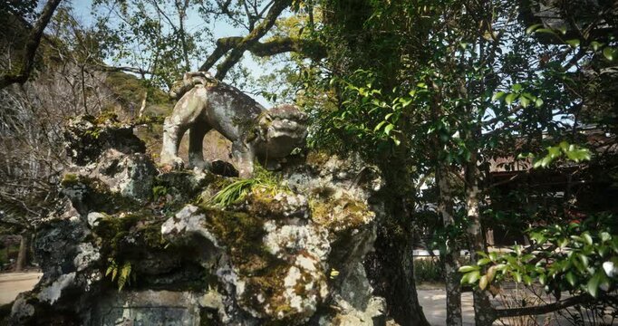 Moss-Covered Stone Guardian Statue at Japanese Temple In Hiroshima