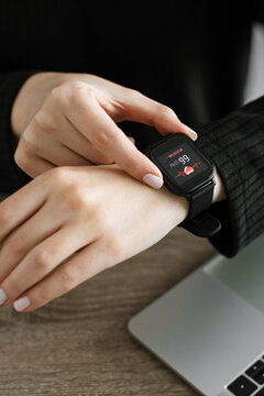 A person checks their heart rate on a smartwatch displaying 99 BPM with a heart icon and waveform