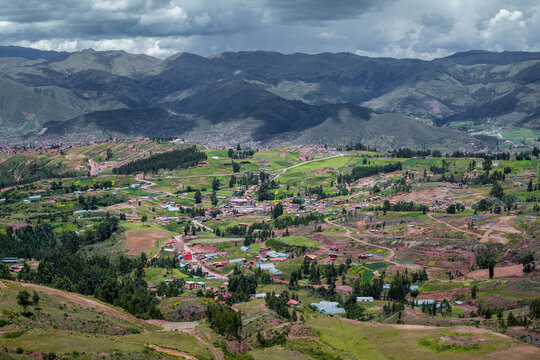 Rural Sacred Valley stretches into the distance with patchwork fields, scattered villages, and cloudy mountain scenery.