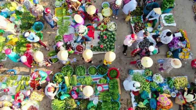 Top-down aerial view of a bustling traditional outdoor market with local vendors in Vietnam.
