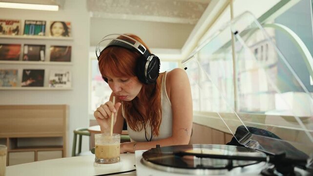 Young woman with headphones listening to vinyl records