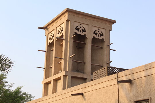 Traditional Arabian Wind Tower Badgir on Heritage Sandstone Building Against Hazy Sky &mdash; Middle East Architecture Photography
