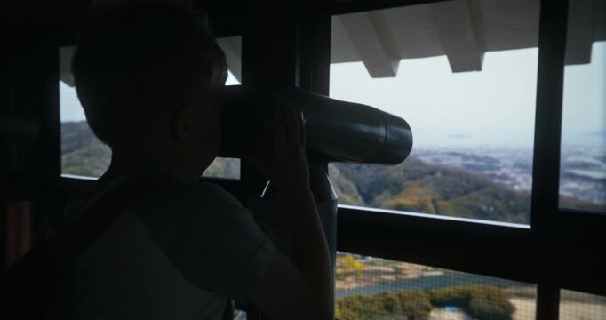 Child Using Binoculars at Observation Deck Overlooking City and Hills