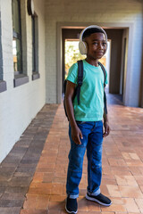 Fototapeta premium African American child boy standing on porch wearing teal tee, black backpack, white headphones
