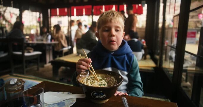 Boy Eating Noodles with Chopsticks in Japanese Restaurant In Hiroshima - Medium Shot