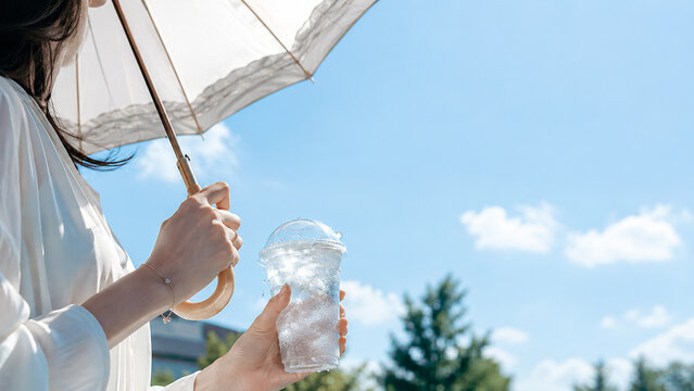 Japanese woman holding icy cold drink and lace parasol under bright summer blue sky, heat protection and refreshment lifestyle concept,晴れた夏の青空の下でレースの日傘とアイスドリンクを手にした日本人女性、熱中症対策と清涼感のライフスタイルコンセプト