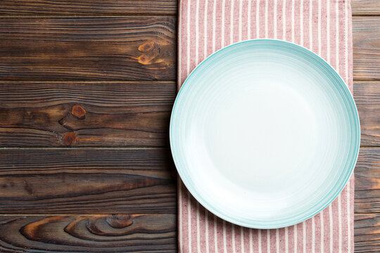 Top view on colored background empty round blue plate on tablecloth for food. Empty dish on napkin with space for your design