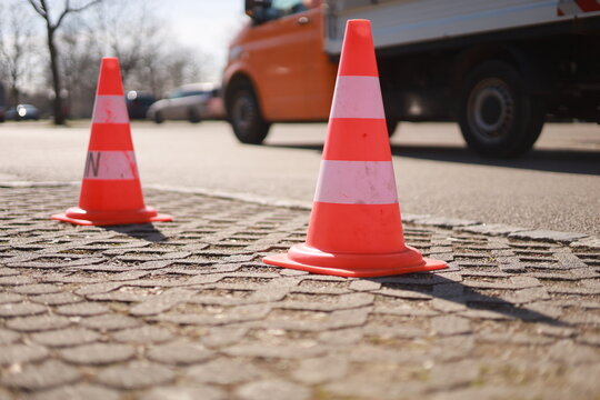 Two orange and white traffic cones are on the road