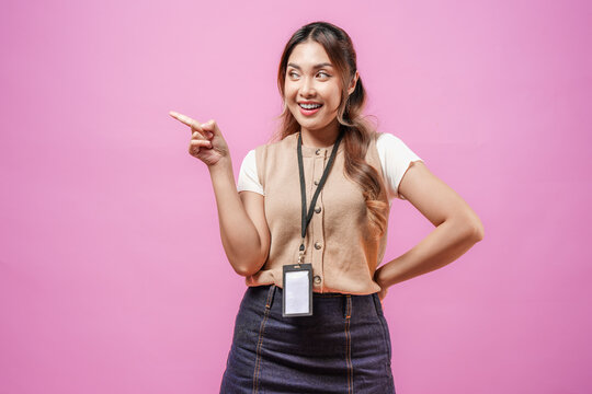 Pretty young Asian woman in a brown shirt pointing to the copy space beside her.
