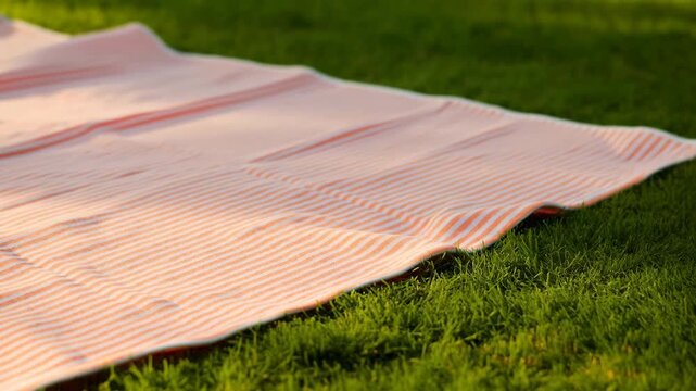 Orange and white striped picnic blanket on grass