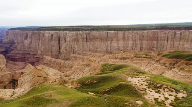 Panoramic sandstone cliff and grassy hummocks under overcast sky