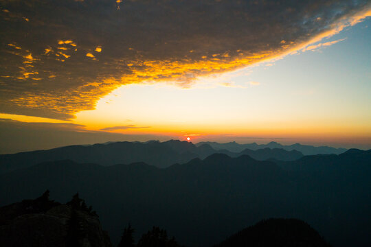 Golden sun rises over layers of hazy mountains